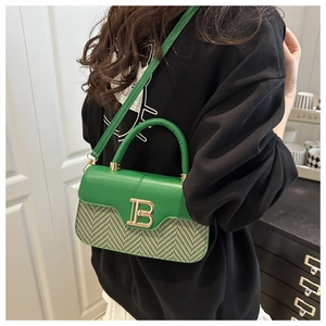 Dettaglio della trama pied-de-poule verde e della fibbia dorata a B sulla borsa alla moda