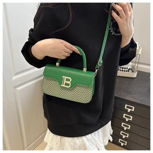 Dettaglio borsa in pelle verde con chiusura dorata logo B e tracolla regolabile