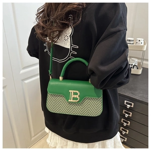 Dettaglio della borsa a tracolla intrecciata verde con fibbia logo B dorata sulla spalla