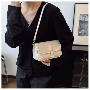 Detailansicht der cremefarbenen Ledertasche mit eleganter Goldschnalle und Riemendetails