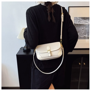 Nahaufnahme der cremefarbenen Ledertasche mit goldener Schnalle auf schwarzem Pullover