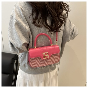 Dettaglio della borsa a tracolla intrecciata rosa con logo B dorato e manico in pelle
