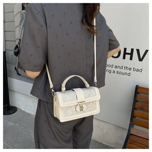 Detail of cream white structured bag showing jacquard pattern and metal twist lock