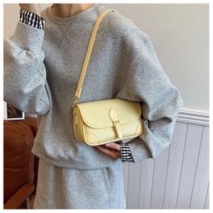Detail der gelben Crossbody-Tasche aus Lychee-Leder mit Schnalle an einem Model