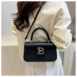 Dettaglio della borsa a tracolla nera con fibbia B dorata e doppia texture in pelle