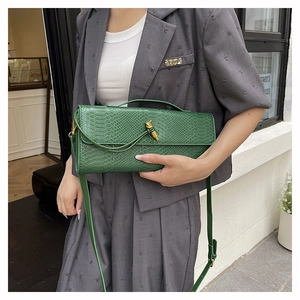Détail du sac à main vert foncé texturé serpent avec boucle nœud dorée