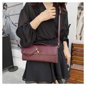Détail du sac bordeaux motif serpent avec fermoir nœud doré et bandoulière fine en cuir