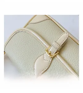 Nahaufnahme der beigen Handtasche mit Lychee-Narbung und eleganter goldener Metallschnalle