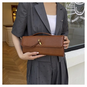 Vue détaillée d'une pochette marron motif serpent avec boucle nœud dorée sur un mannequin