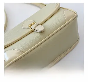 Detailansicht der cremeweißen Achseltasche mit Lychee-Leder und goldener Schnalle