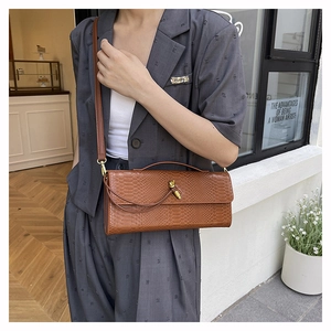 Vue détaillée du sac à rabat marron effet serpent avec boucle nœud dorée sur modèle