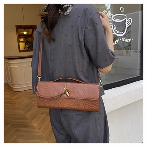 Détail d'un sac à main marron effet serpent avec fermoir tournant doré et bandoulière