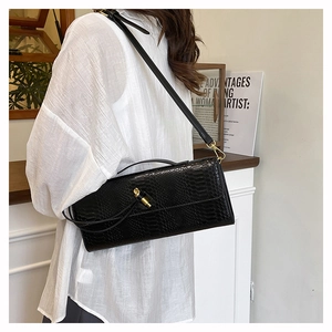Gros plan sur la texture serpent noir et boucle en métal doré sur ce sac pochette