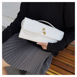 Détail de la pochette blanche à relief serpent avec une boucle en métal doré noué