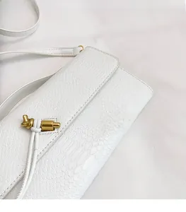 Gros plan sur la texture cuir serpent blanc avec boucle en nœud métallique doré