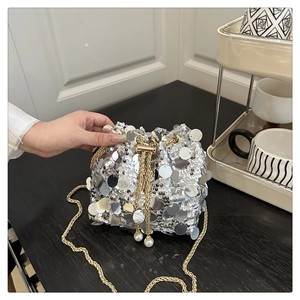 Detail of silver sequin bucket bag with gold chain and pearl drawstring closure