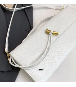 Détail de la texture crocodile blanc et du fermoir doré torsadé sur le sac à main