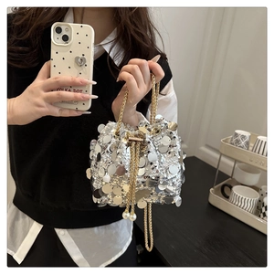 Detail of silver sequin bucket bag featuring gold chain strap and pearl drawstring tassels