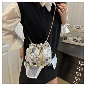 Detailed view of silver sequin bucket bag with gold chain and pearl drawstring on model