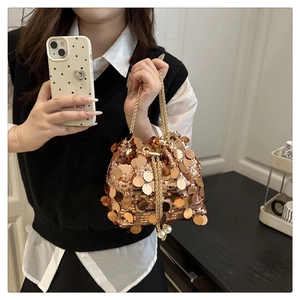 Close-up of rose gold sequin bucket bag with gold chain and pearl drawstring details