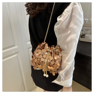 Detailed close-up of a sequin bucket bag with pearl drawstring and gold chain strap