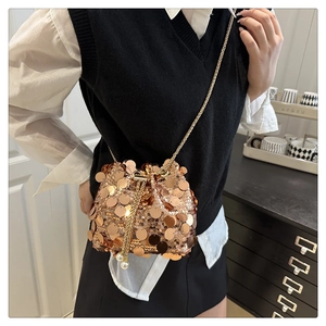Macro detail of rose gold bucket bag featuring large sequins and pearl chain strap
