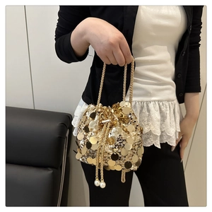 Detail of gold sequin bucket bag featuring chain strap and pearl drawstring charms