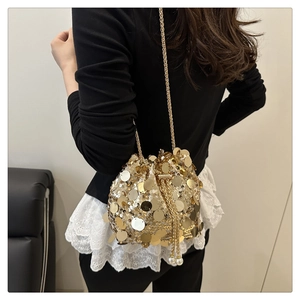 Detail of golden sequin bucket bag featuring drawstring pearls and metal chain strap