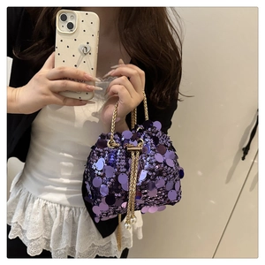 Detail of purple sequin bucket bag with gold chain strap and elegant pearl drawstring