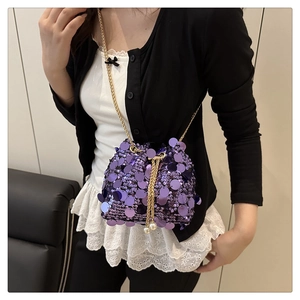 Detail of purple sequin bucket bag featuring a gold chain and white pearl tassel charm