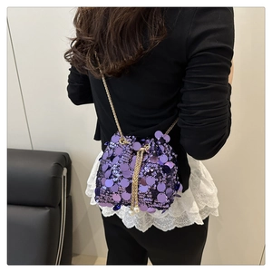 Detail of purple sequin bucket bag with gold chain strap and pearl drawstring accents