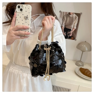 Detail of black sequined bucket bag with faux pearl drawstring and gold chain strap