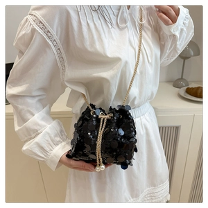 Detail view of black sequin bucket bag with gold chain strap and pearl drawstring detail