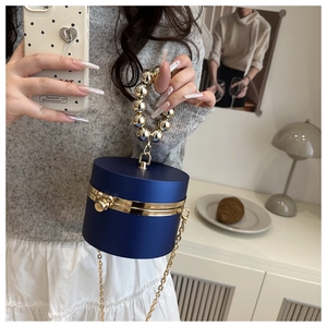 Detalle de bolso caja de acrílico azul marino con borde dorado y asa de perlas de lujo