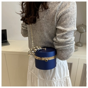 Detalle del bolso de fiesta redondo azul marino con marco dorado y asa de bolas metálicas