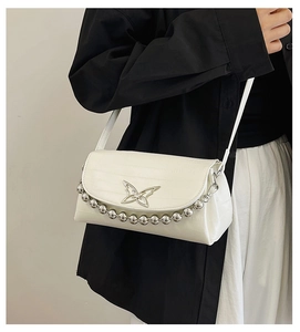 Close-up of white embossed crossbody bag with silver butterfly and bead chain details