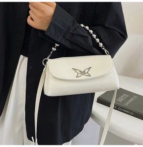 Detail of white crocodile pattern bag with silver butterfly buckle and beaded handle