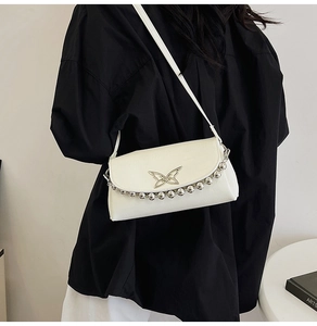 Close-up of the cream shoulder bag featuring a silver butterfly clasp and bead chain detail