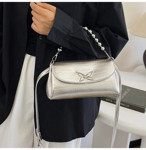 Detailed view of silver metallic pleated crossbody bag with hollow butterfly metal accent