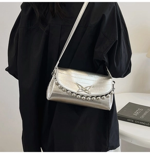 Detailed close-up of metallic silver shoulder bag featuring butterfly logo and bead chain