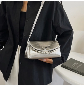 Close-up of metallic silver leather crossbody bag with butterfly buckle and bead chain