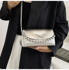 Detail of silver metallic crossbody bag featuring butterfly logo and mirror bead chain decoration