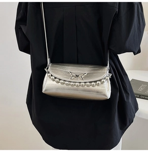 Detail of silver metallic crossbody bag with textured finish and decorative beads