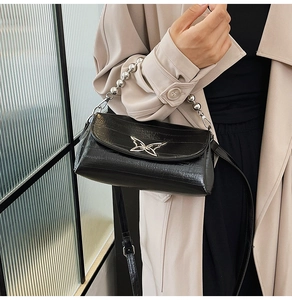 Detail of black crocodile texture handbag with silver butterfly clasp and beaded handle