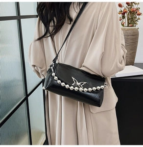 Detail of black crocodile texture bag featuring butterfly metal buckle and silver bead chain
