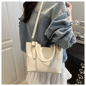 Detail view of cream white lychee texture bucket bag with handles and strap worn by model