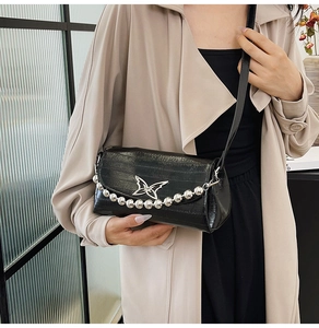 Detail of black crocodile texture bag featuring silver butterfly clasp and beaded chain
