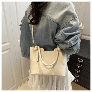 Close-up of cream lychee leather bucket bag with reinforced stitching and handle details