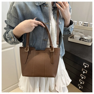 Detail of brown lychee grain leather tote bag with gold hardware and shoulder strap