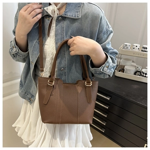 Detail of brown lychee grain leather tote bag with gold hardware and slim strap